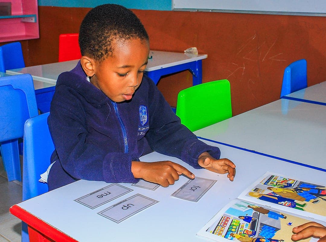 A child reading sight-word cards beside an open picture book