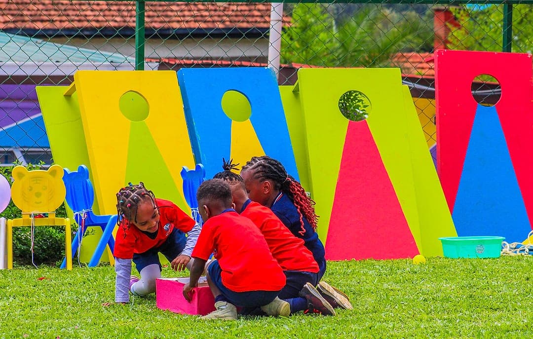 Children crouched together over a shared activity on the grass