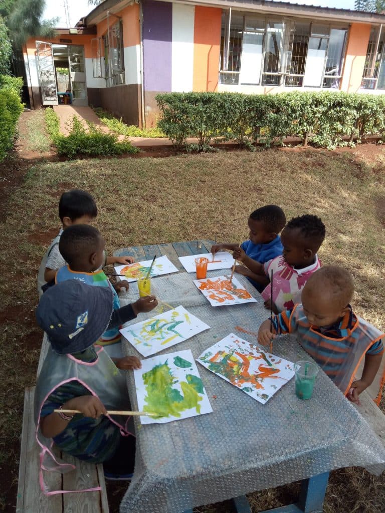 Children painting with watercolours at an outdoor table