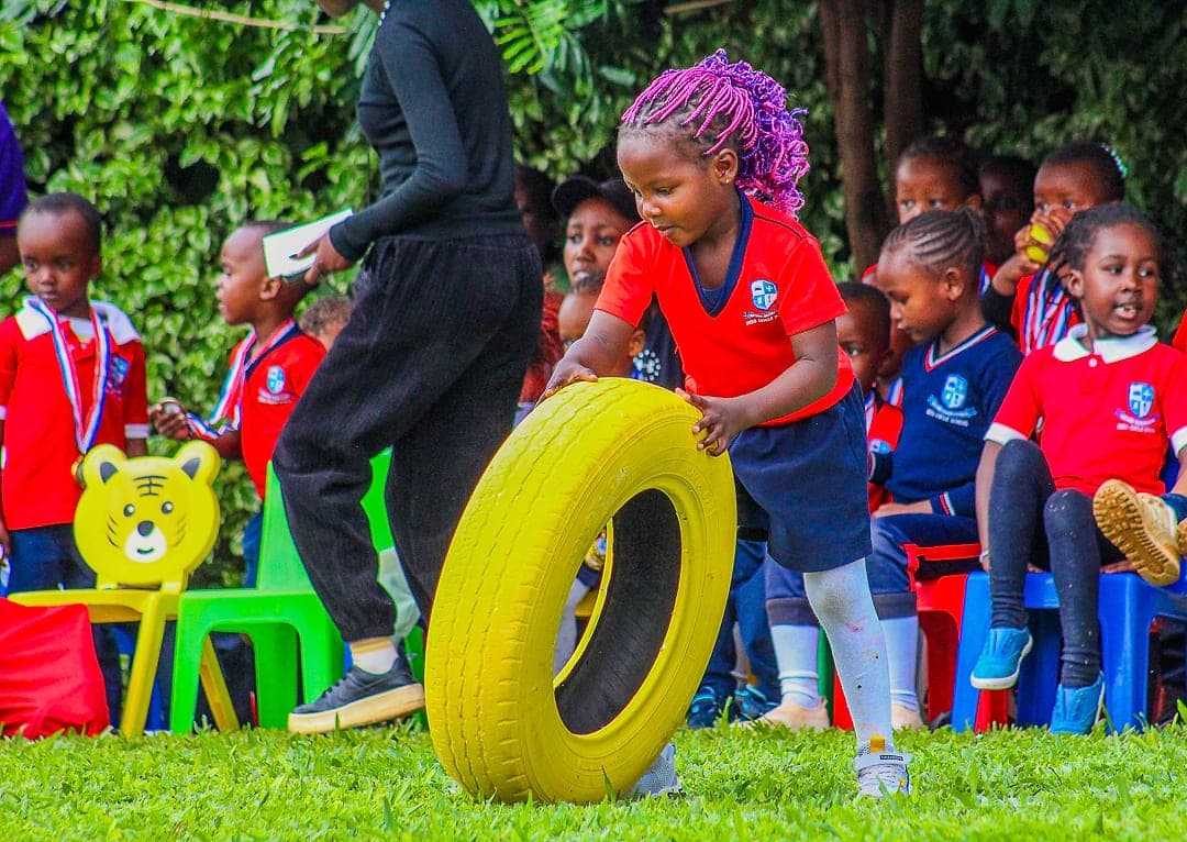 A child rolling a large tyre across the grass on sports day